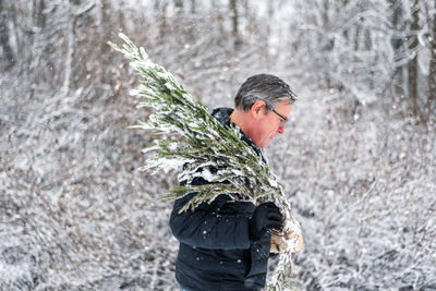 Man with umbrella standing on snow covered land