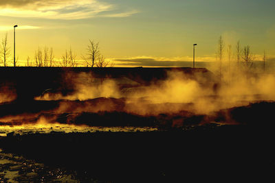 Smoke emitting from landscape against sky