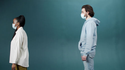 Side view of man and woman wearing mask against blue background