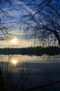 Reflection of trees in lake at sunset