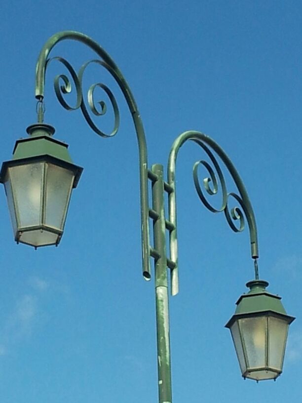 low angle view, lighting equipment, clear sky, street light, blue, lamp post, copy space, electric light, electricity, illuminated, pole, sky, electric lamp, outdoors, no people, day, high section, lamp, metal, hanging