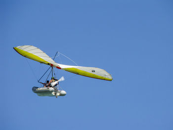 Low angle view of aircraft in flight against clear blue sky