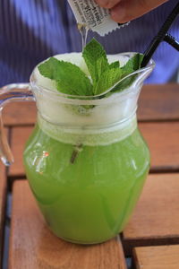 Cropped image of person pouring liquid in juice on table