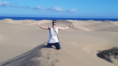 Woman standing on sand dune in desert against sky