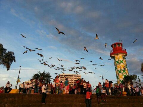 large group of people, sky, architecture, built structure, building exterior, bird, person, men, low angle view, flying, lifestyles, cloud - sky, leisure activity, mixed age range, cultures, cloud, tradition, outdoors, flag