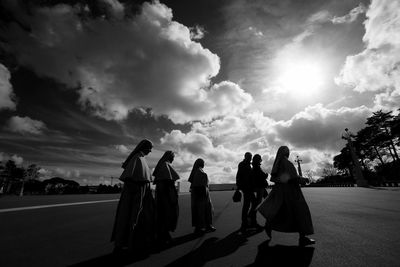 Nuns walking on road against sky