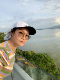 Young woman looking away while standing by plants against sky