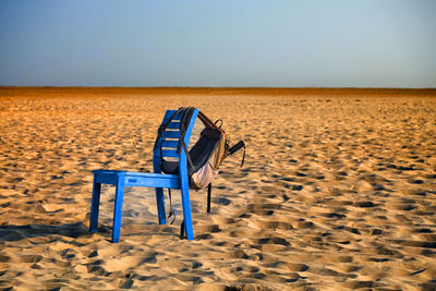 Empty chair on beach against clear sky