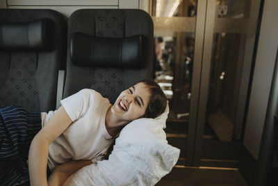 Happy girl laughing while resting on seat in train