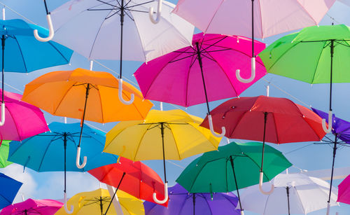 Low angle view of multi colored umbrellas hanging against sky