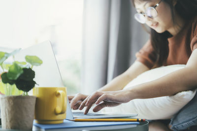 Midsection of woman sitting on table at home