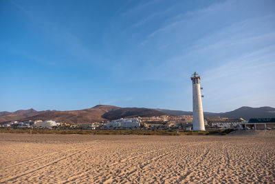 Lighthouse by sea against sky