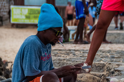 Side view of man holding mobile phone at beach