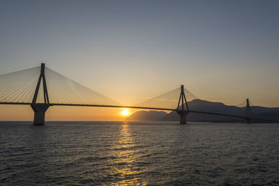 Cable-stayed bridge over river against sky during sunset