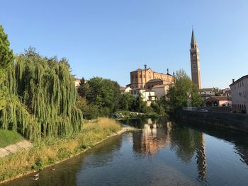 Canal amidst trees and buildings against sky