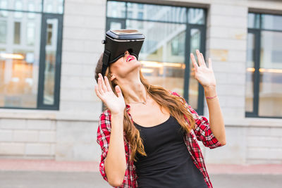 Young woman wearing hat standing against built structure