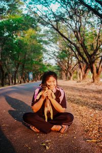 Woman holding puppy while sitting on road