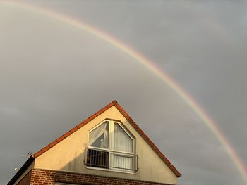 Low angle view of rainbow over building against sky