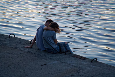 Rear view of couple sitting on the lake