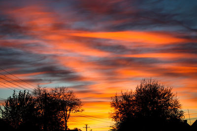 Low angle view of silhouette trees against dramatic sky