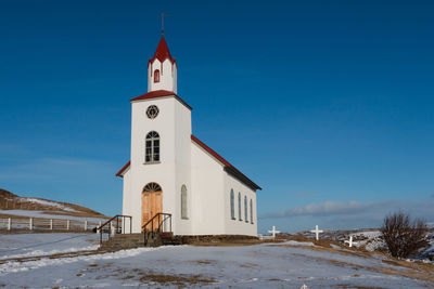 Church on snow covered landscape against sky during winter