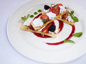 Close-up of puff pastries with strawberries served in plate on table