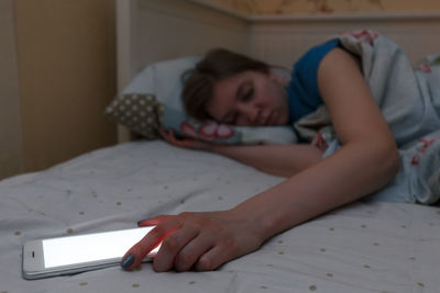 Cute exhausted girl fell asleep with the phone in her hand. selective focus on phone. white screen.