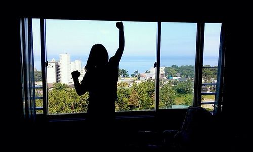 Silhouette woman looking through window