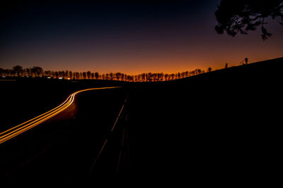 Silhouette road against sky at sunset