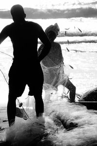 Silhouette people fishing at beach