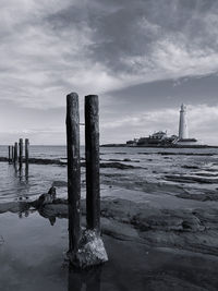 Wooden posts on beach against sky