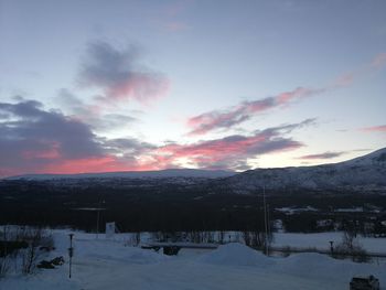 Scenic view of snow covered field against sky at sunset