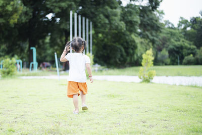 Rear view of boy running on field