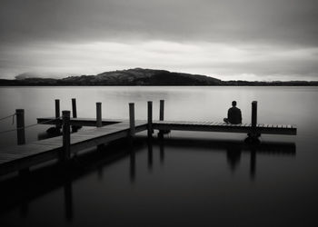 Pier on lake against cloudy sky