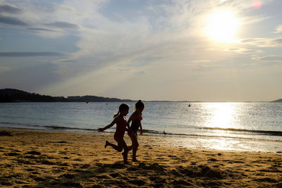 Sisters running on shore at beach