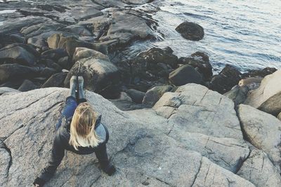 High angle view of young woman sitting on rock at beach