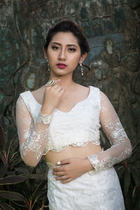 Portrait of young woman standing against carved wall