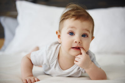 Portrait of baby girl lying on bed at home