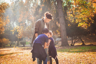 Woman with playful siblings standing in park during autumn