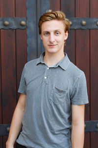 Portrait of young man standing against door