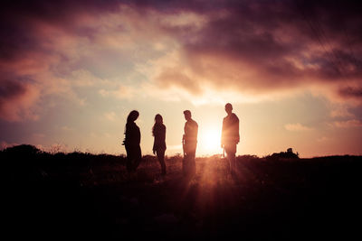 Silhouette people standing on field against sky during sunset