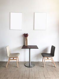 Blank picture frames on wall by empty chairs and table at home