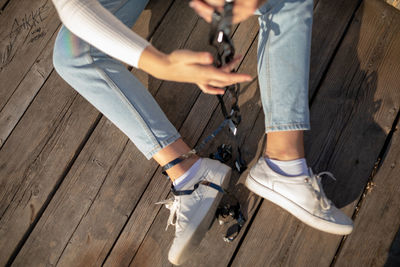 Low section of woman with tape tangled sitting on wood