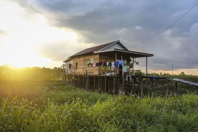 House on field against sky during sunset