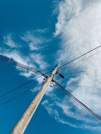 Low angle view of telephone pole against blue sky