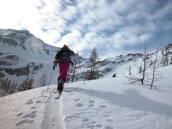 Rear view of person on snowcapped mountain against sky