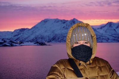 Portrait of face covered woman standing against lake and mountain during sunset