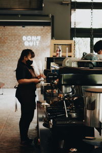 Side view of woman standing by coffee at cafe