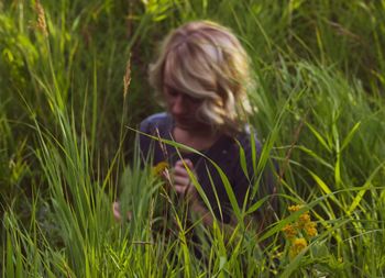 Portrait of young woman holding plant on field