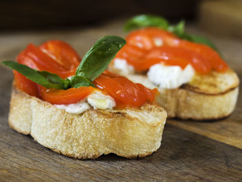 Close-up of bruschetta with feta cheese and red bell peppers served on cutting board